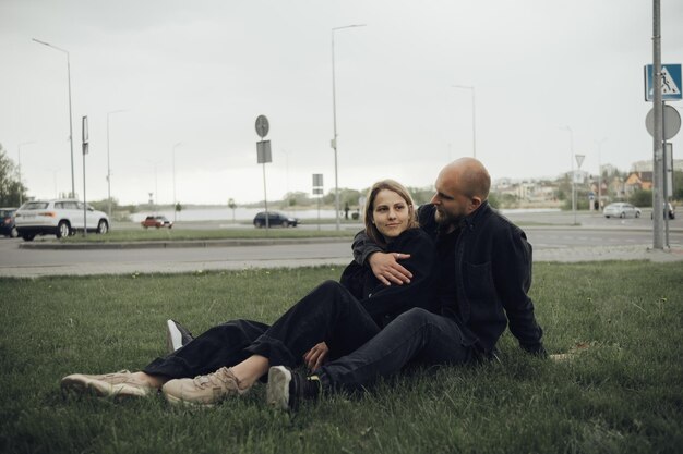 Lovers hug sitting on the grass and look into the camera