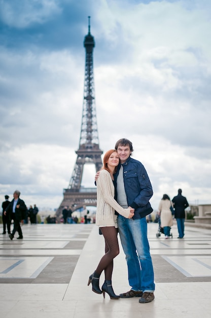 lovers look at camera in paris with the eiffel tower in the background