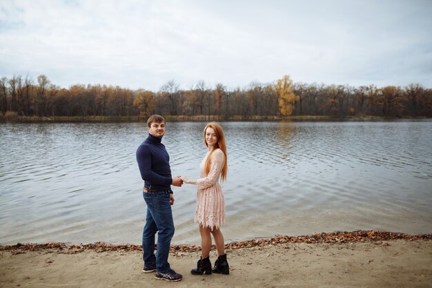 Lovers stand on the shore of the lake with a beautiful view and hold hands