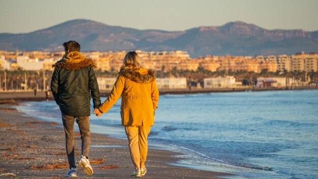 lovers walking along the shore of the beach holding hands in winter