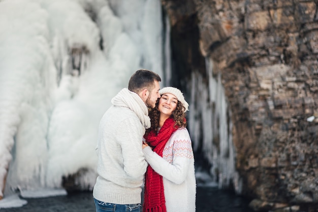 lovers in winter at the waterfall for a walk