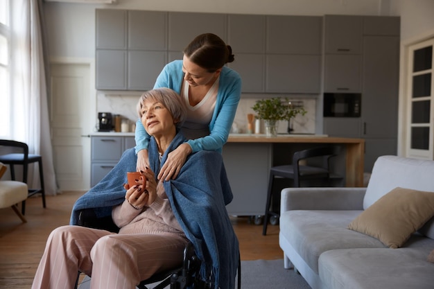 Loving adult daughter hugging old mother with disability sitting in wheelchair