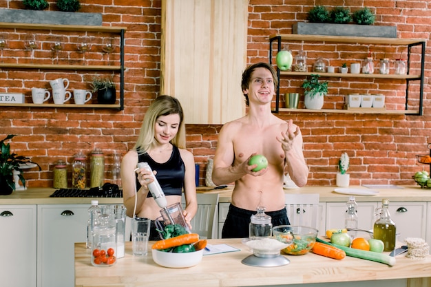 Loving afro american couple preparing green salad together in loft kitchen ,the boy throws the apple up