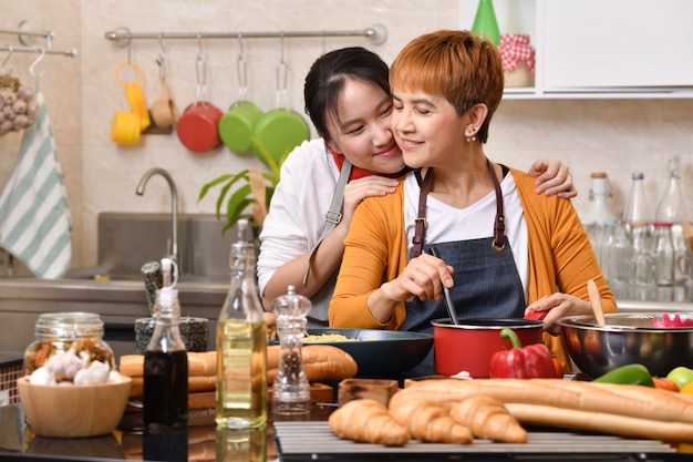 Photo loving asian family of mother and daughter cooking in kitchen making healthy food together feeling fun