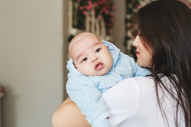 家で赤ん坊の息子を保持している愛情のあるアジアの母親。