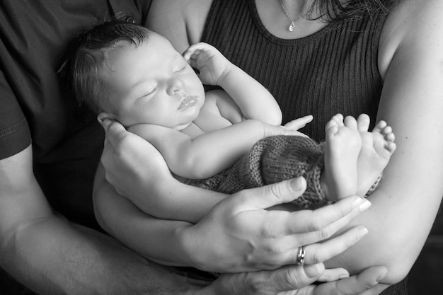 Loving baby sleeping in parents hands Closeup picture Happy mother and father and they newborn baby