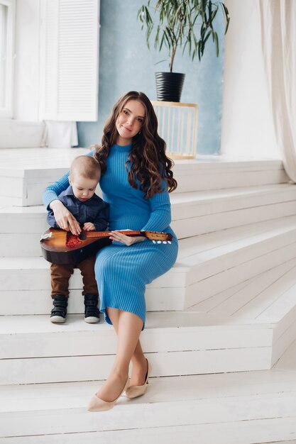 Loving beautiful mother playing music instrument with her son