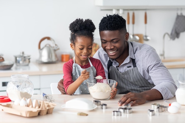 Loving black father making cookies with his little daughter