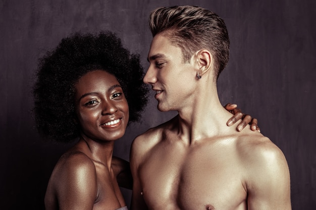 Loving boyfriend. Delighted handsome man standing half face while smiling to his girlfriend