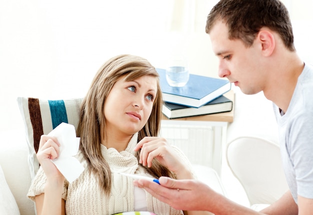 Loving boyfriend holding a thermometer of his ill girlfriend 