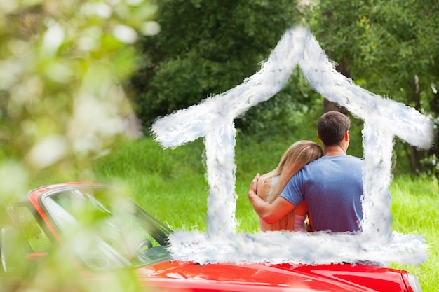 Loving couple admiring nature while leaning on their cabriolet against house outline in clouds