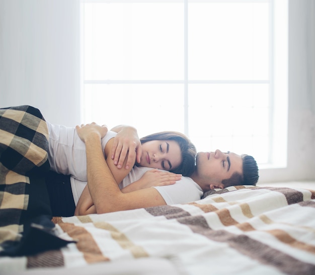 Una coppia di innamorati è sdraiata sul letto. camera da letto luminosa e accogliente. comfort familiare e amore
