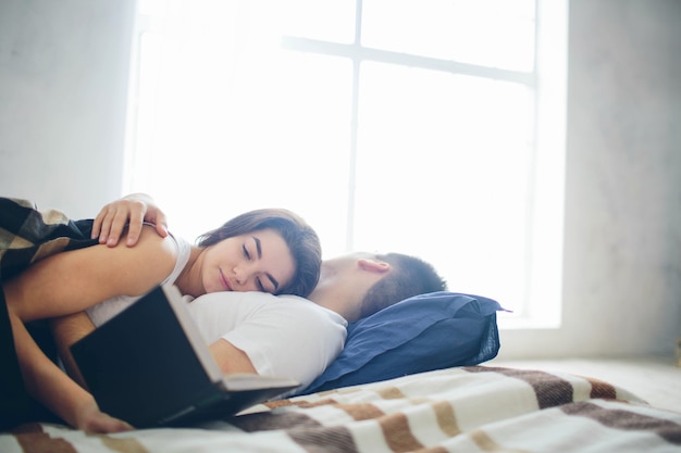 A loving couple are lying on the bed