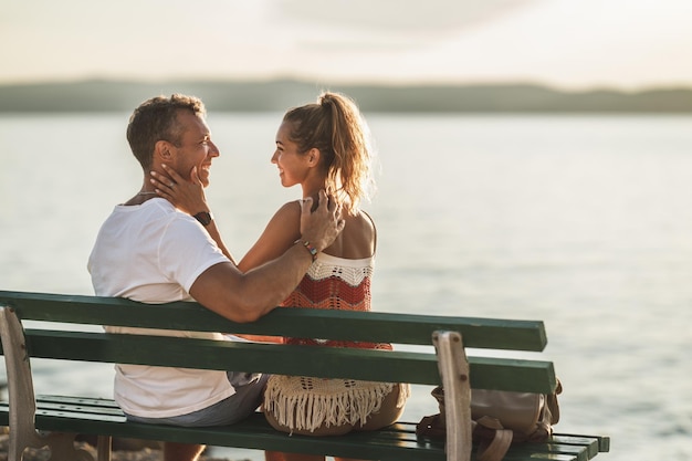 A loving couple are sitting on bench and enjoying a summer vacation near the sea beach.