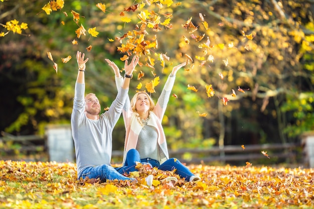 A loving couple in an autumn park lies on the leaves.