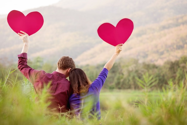 Coppia amorosa. bella giovane coppia di amore in possesso di cuori di carta e sorridente in natura all'aperto tono d'annata, concetto di san valentino