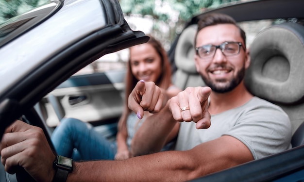 Loving couple in a convertible car pointing at youthe concept of choice