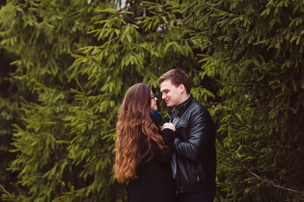 Loving couple embracing on fir trees