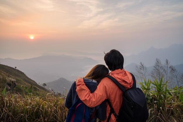 Loving couple embracing on the mountain at sunset.