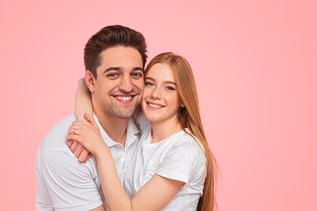 Loving couple embracing in pink studio