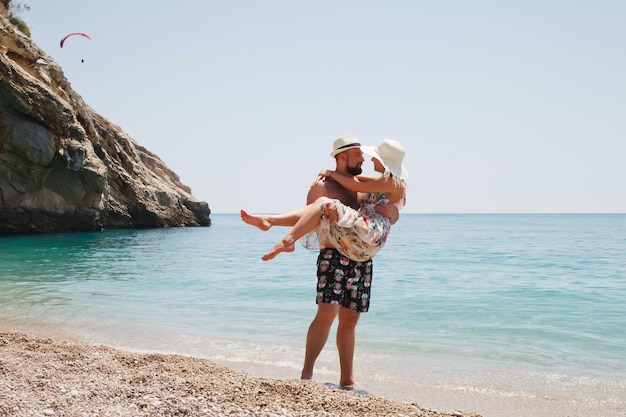 海の背景を歩く贅沢な景色とラグナのビーチで新婚旅行を楽しんでいる愛情のあるカップル