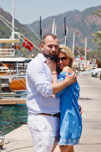 Loving couple enjoying honeymoon on embankment with luxury yachts