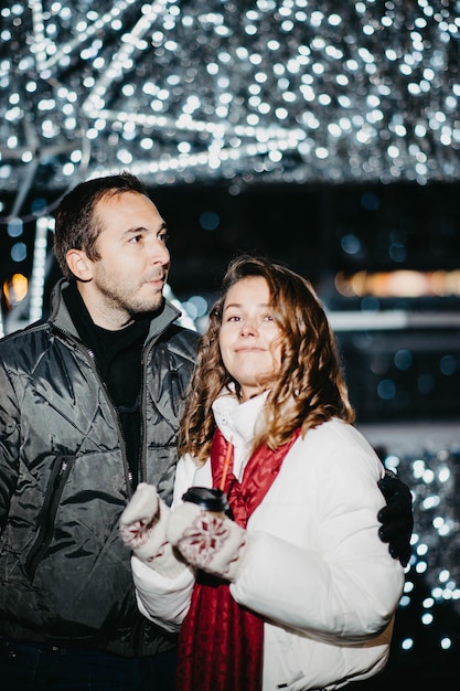 Coppia di innamorati in una città festosa con le luci di capodanno nella sera d'inverno. i coniugi in inverno si coagulano