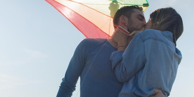 Loving couple flying a kite at beach and having fun on autumn day