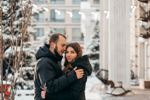 雪に覆われた街を背景に優しい抱擁で愛するカップル