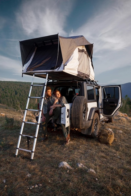 loving couple of girl and guy of travelers sitting in car in mountains