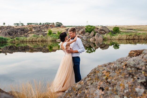 Loving couple, guy and girl kiss and hug on the background of large stones on the wedding day.