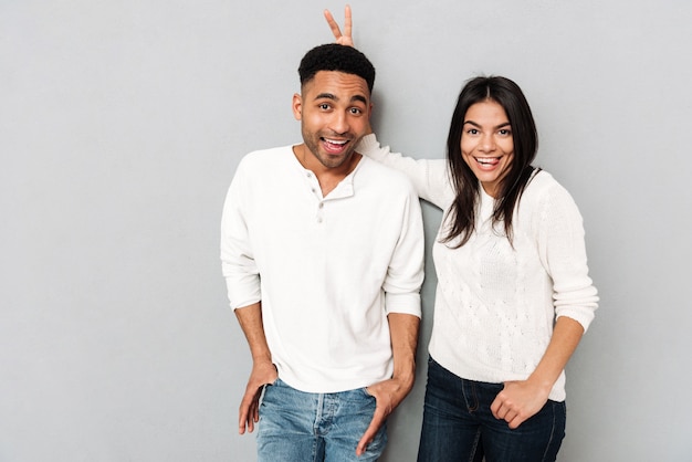 Loving couple have fun over grey wall