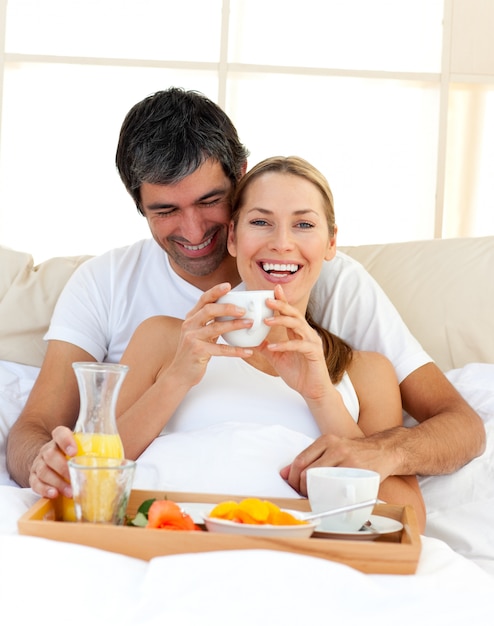 Loving couple having breakfast lying in the bed