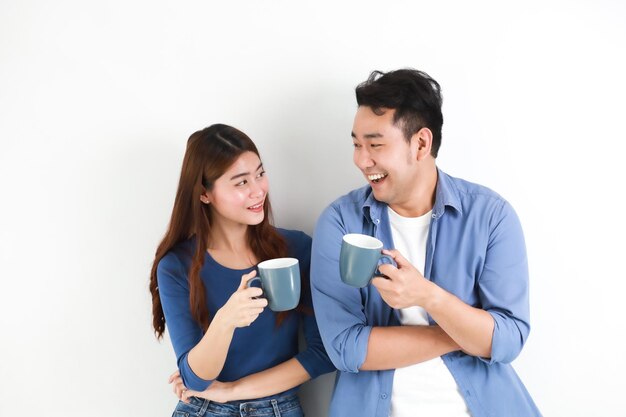 Photo loving couple holding coffee cups while standing against white background