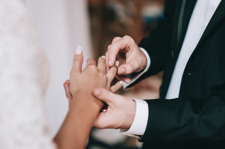 Photo loving couple holding hands with rings against wedding dress