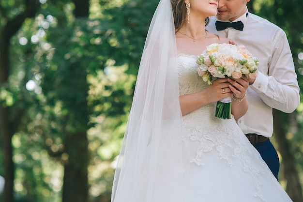 Loving couple holding hands with rings against wedding dress