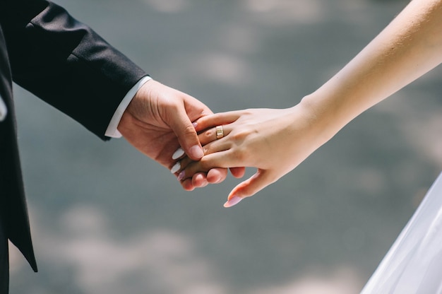Влюбленная пара, держась за руки с кольцами против свадебного платья