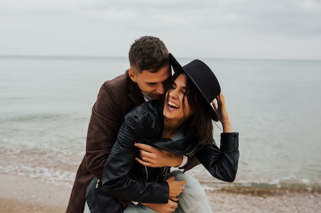 Loving couple is having fun and hugging on the empty sandy sea beach