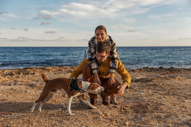 愛情のあるカップルは、ビーチで犬と遊んでいる白人の人々 動物のライフ スタイルと自然の概念