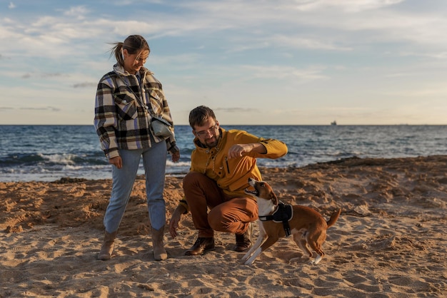 Loving couple is playing with their dog at the beach caucasian people people animal lifestyle and nature concept