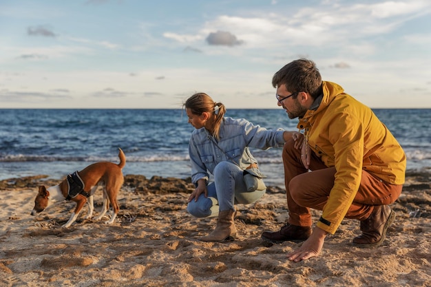 Влюбленная пара играет со своей собакой на пляже кавказские люди люди животный образ жизни и концепция природы