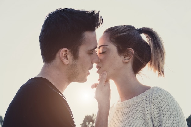 Photo loving couple kissing outdoor at sunset - concept about people, love and lifestyle