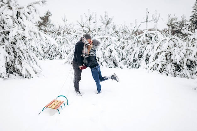 A loving couple kissing in a snowy beautiful forest in winter