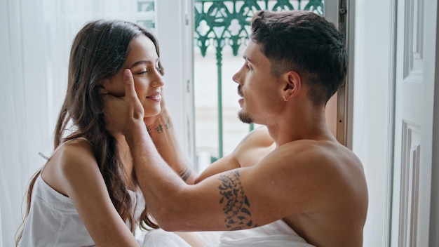 Loving couple kissing at window interior closeup tender man stroking wife