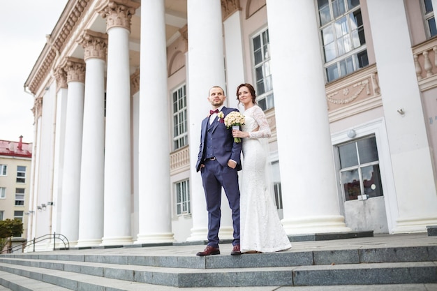 Loving couple of newlyweds walks in the city near columns