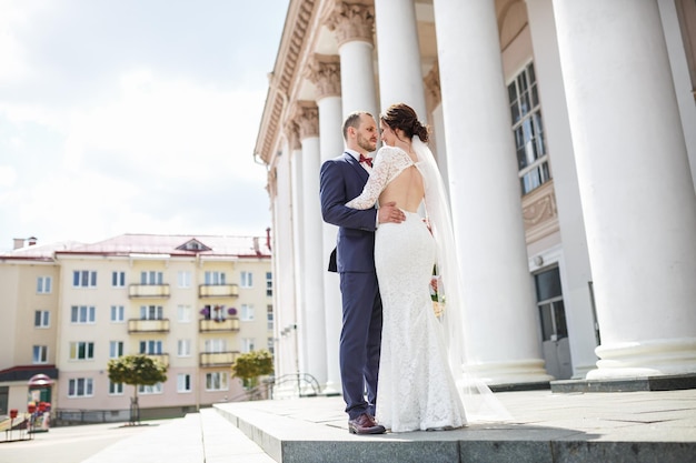 新婚夫婦の愛情のあるカップルが柱の近くで街を歩く