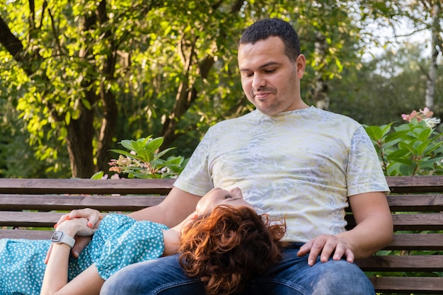 Loving couple on a park bench look at each other with tenderness