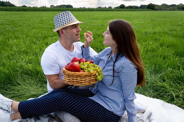 Photo loving couple at a picnic in the park wine and fruit in a wicker basket a wonderful evening spent in nature