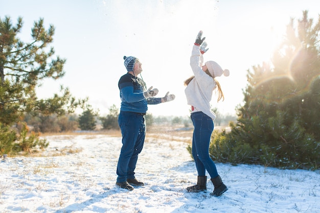 愛するカップルが森で冬に雪玉を再生します。