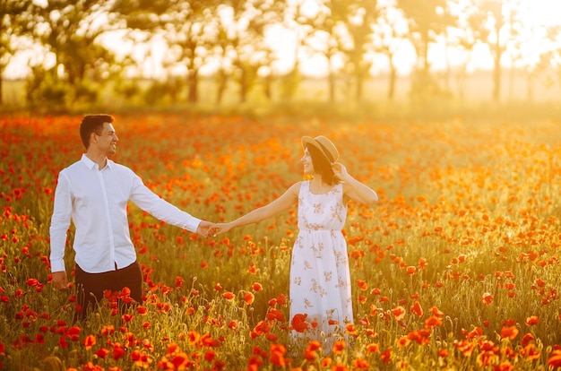 Loving couple in the poppy field at sunset Enjoying time together love and lifestyle